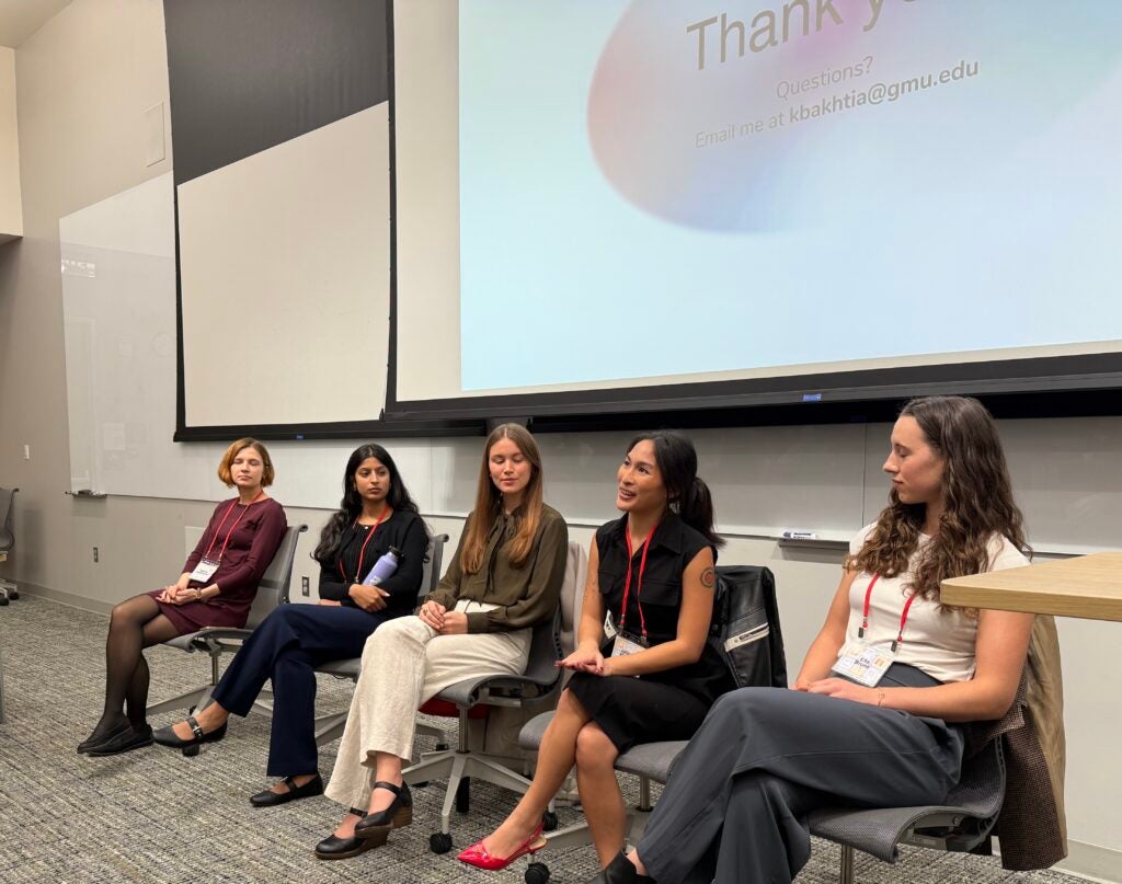 Five students in business-wear sitting as speakers in a panel.